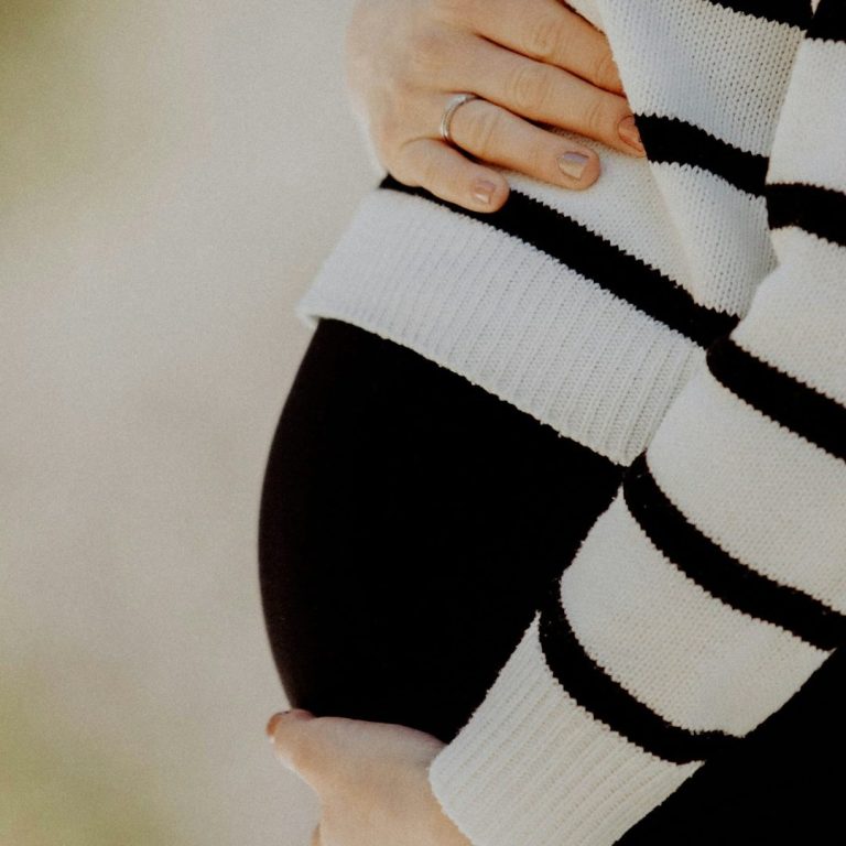 Schwangere legt ihre Hände auf ihren Babybauch