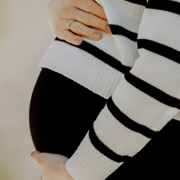 Schwangere legt ihre Hände auf ihren Babybauch
