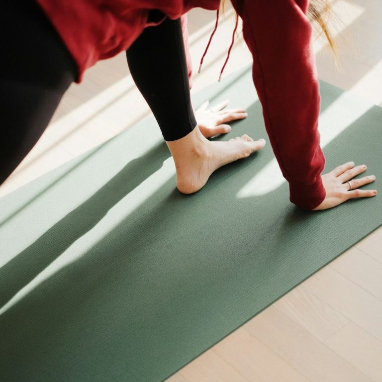Frau in Sportkleidung macht Yoga auf einer Matte